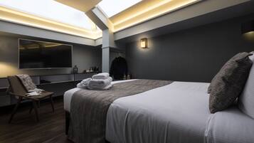 A modern hotel room with a large bed, a flat-screen TV, a desk, and a chair.