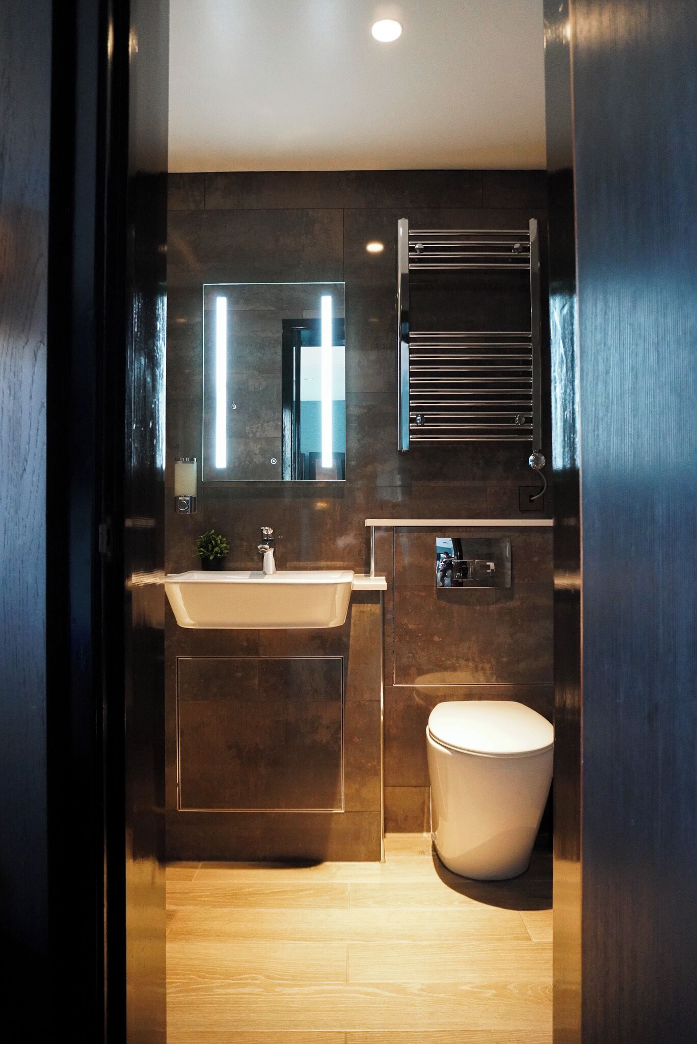 A modern bathroom with a large mirror, a bathtub, a toilet, and a towel rack.