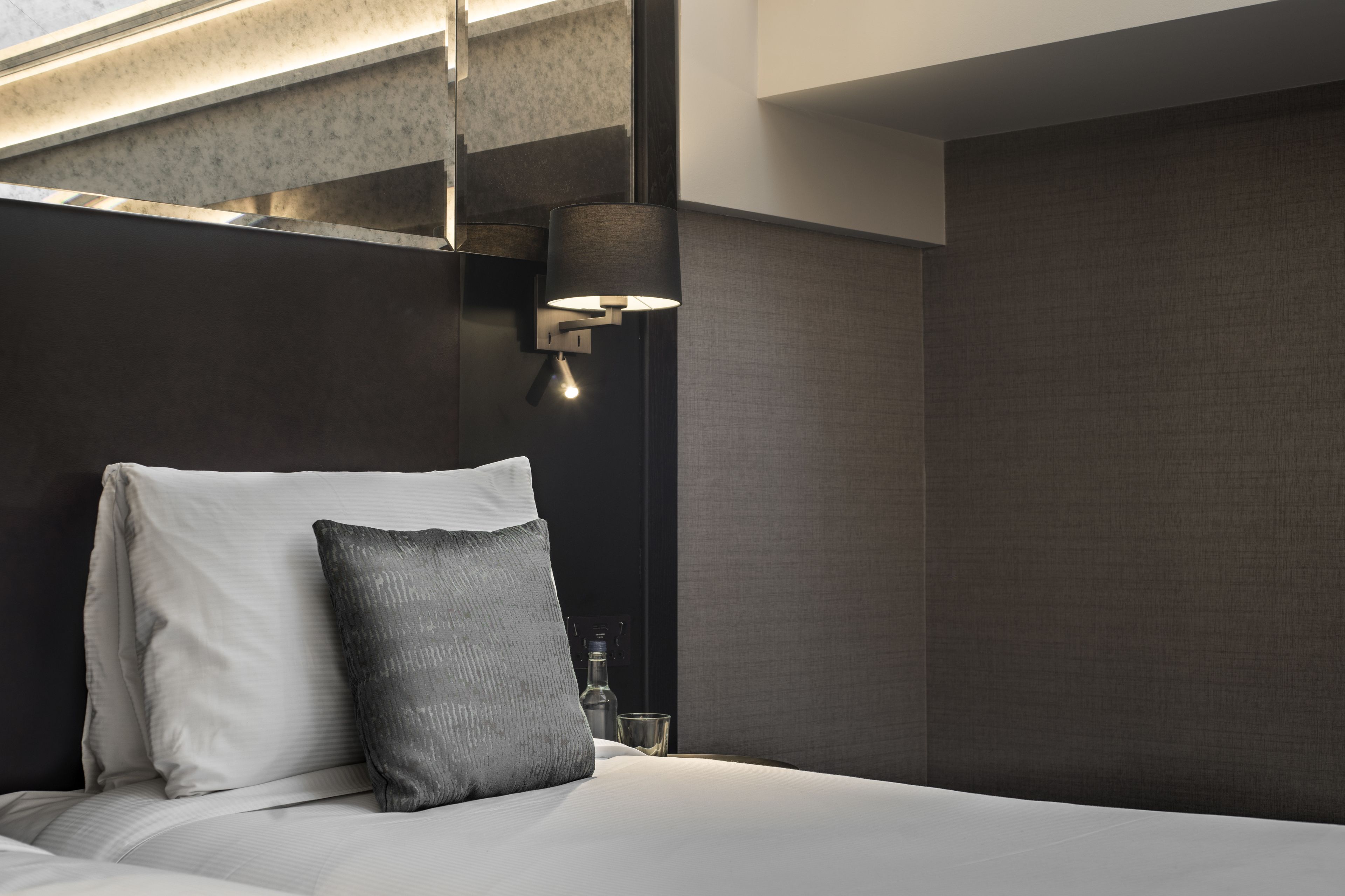 Ein modernes Hotelzimmer mit einem großen Bett, einer Wandlampe und einer strukturierten Wand.