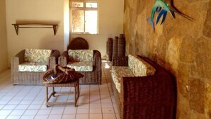 A living room with two sofas, a small table, and a stone wall with a decorative bird sculpture. - Apartamento Porto das Dunas - SBHS (Aquiraz)