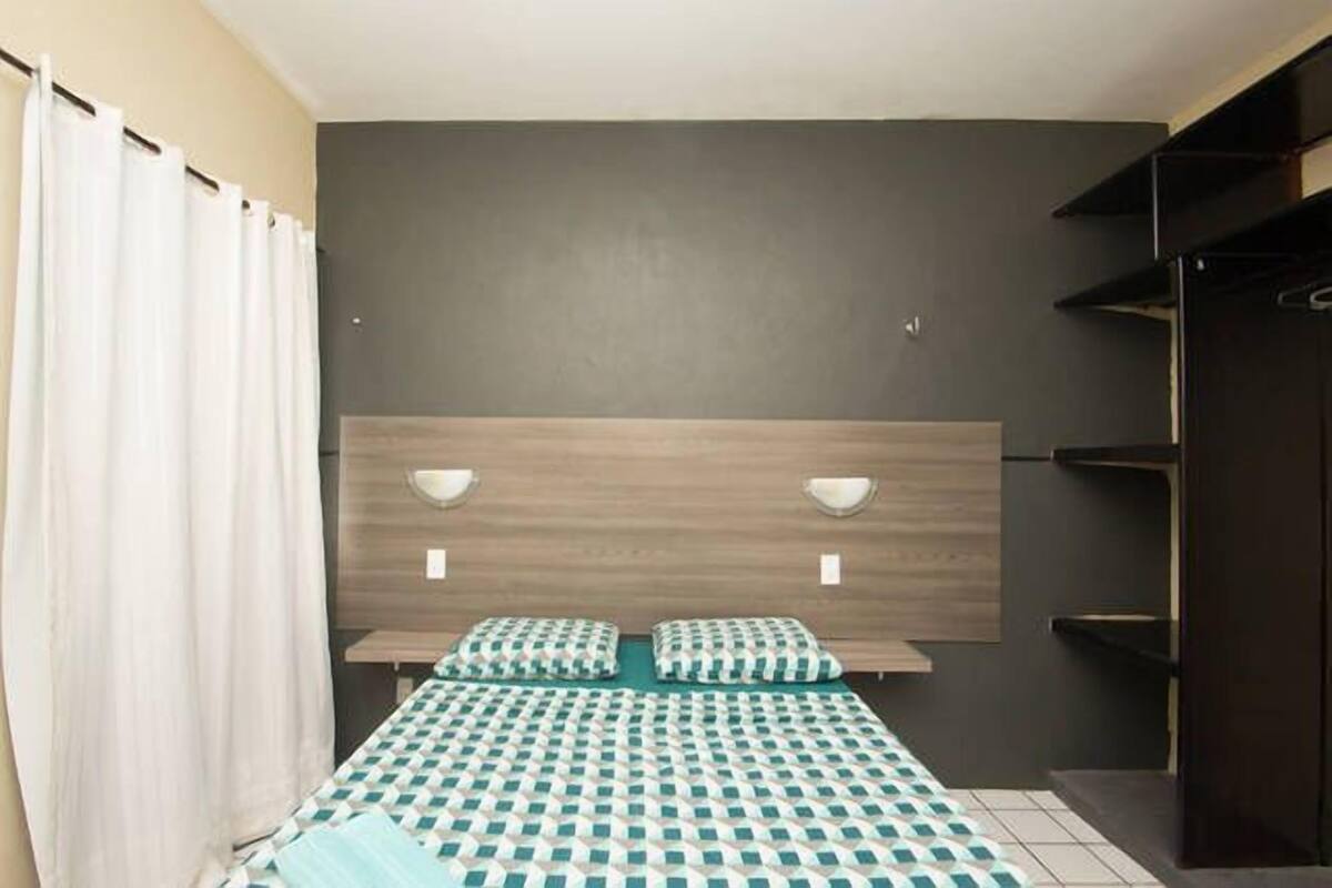 Une chambre d’hôtel comprenant un lit, deux tables de chevet, une tête de lit et une armoire.