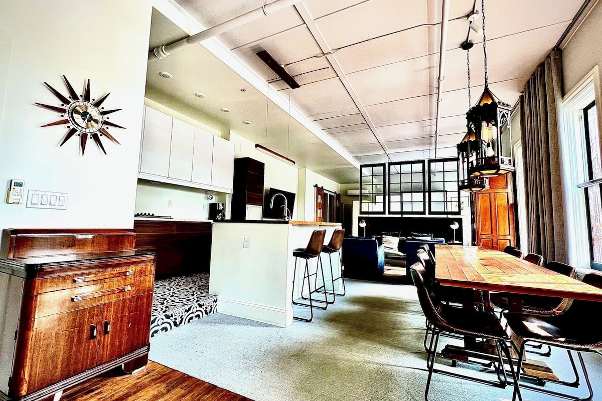 A spacious kitchen with modern appliances, a dining area with a wooden table and chairs, and a large window providing natural light.