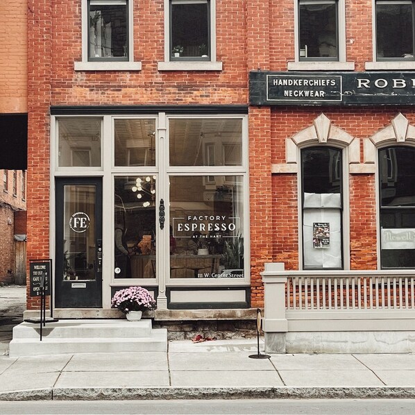 A brick building with a storefront labeled "FACTORY ESPRESSO AT THE HART" and "HANDKERCHIEF NECKWEAR".
