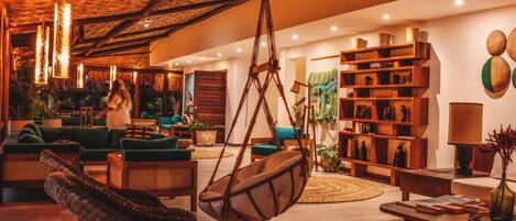 Una sala de estar acogedora con un sillón colgante, un sofá y una mesita de centro. Hay libros y objetos decorativos en las estanterías.