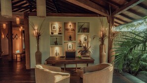 A modern interior with a wooden desk, two upholstered chairs, and a wall decorated with framed artwork and plants.