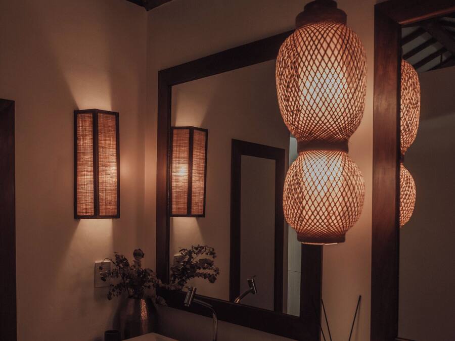 Un baño con tocador de madera, un espejo grande y dos apliques de pared.