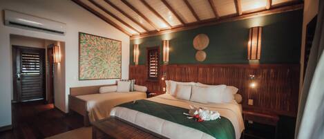 A hotel room with a wooden ceiling, a large bed with a green bedspread, two bedside tables, and a bench.