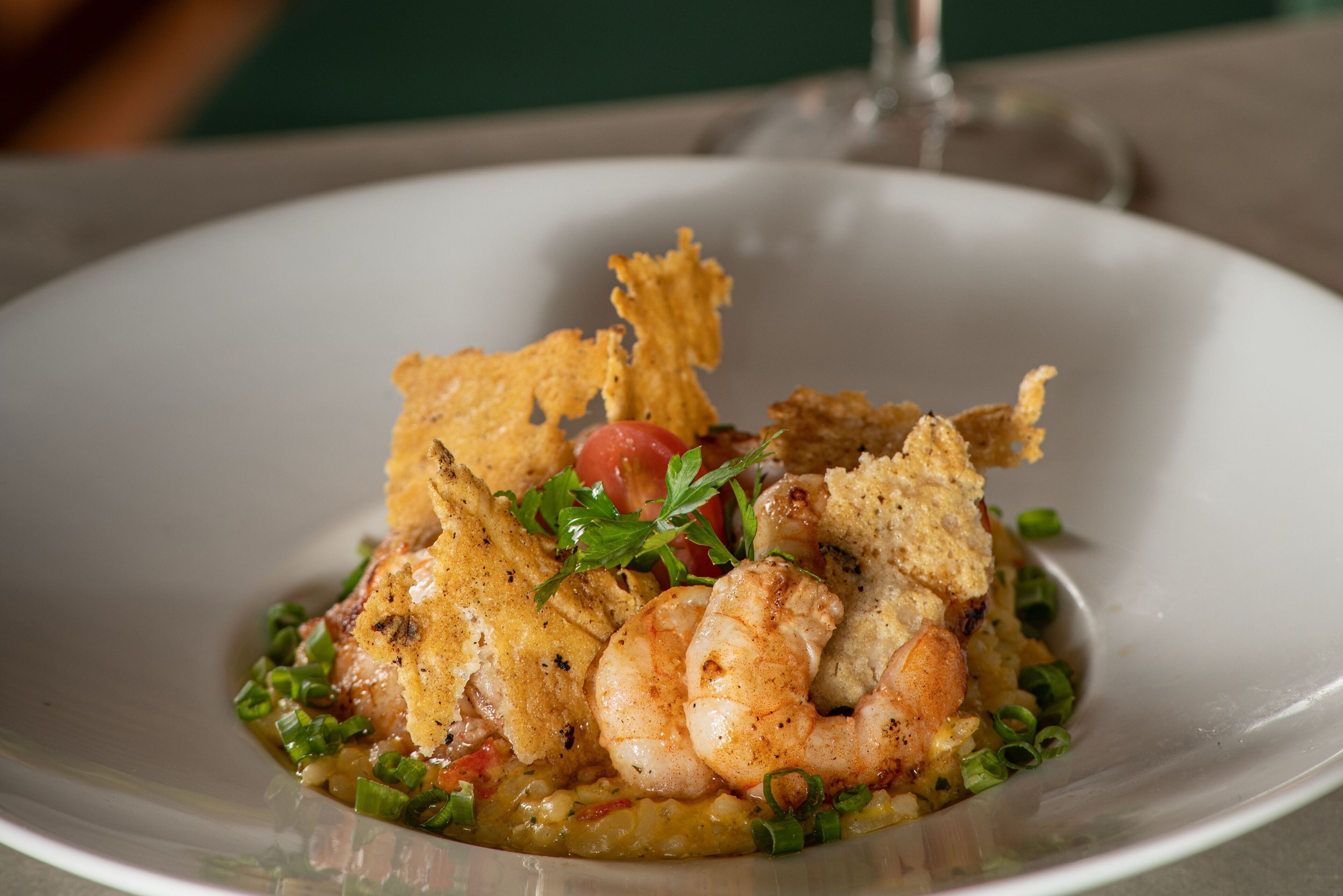 Une assiette de nourriture comprenant des crevettes, des légumes verts et une garniture.