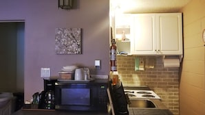 Une cuisine de taille réduite, équipée d’un four à micro-ondes, d’une cuisinière et de meubles blancs.