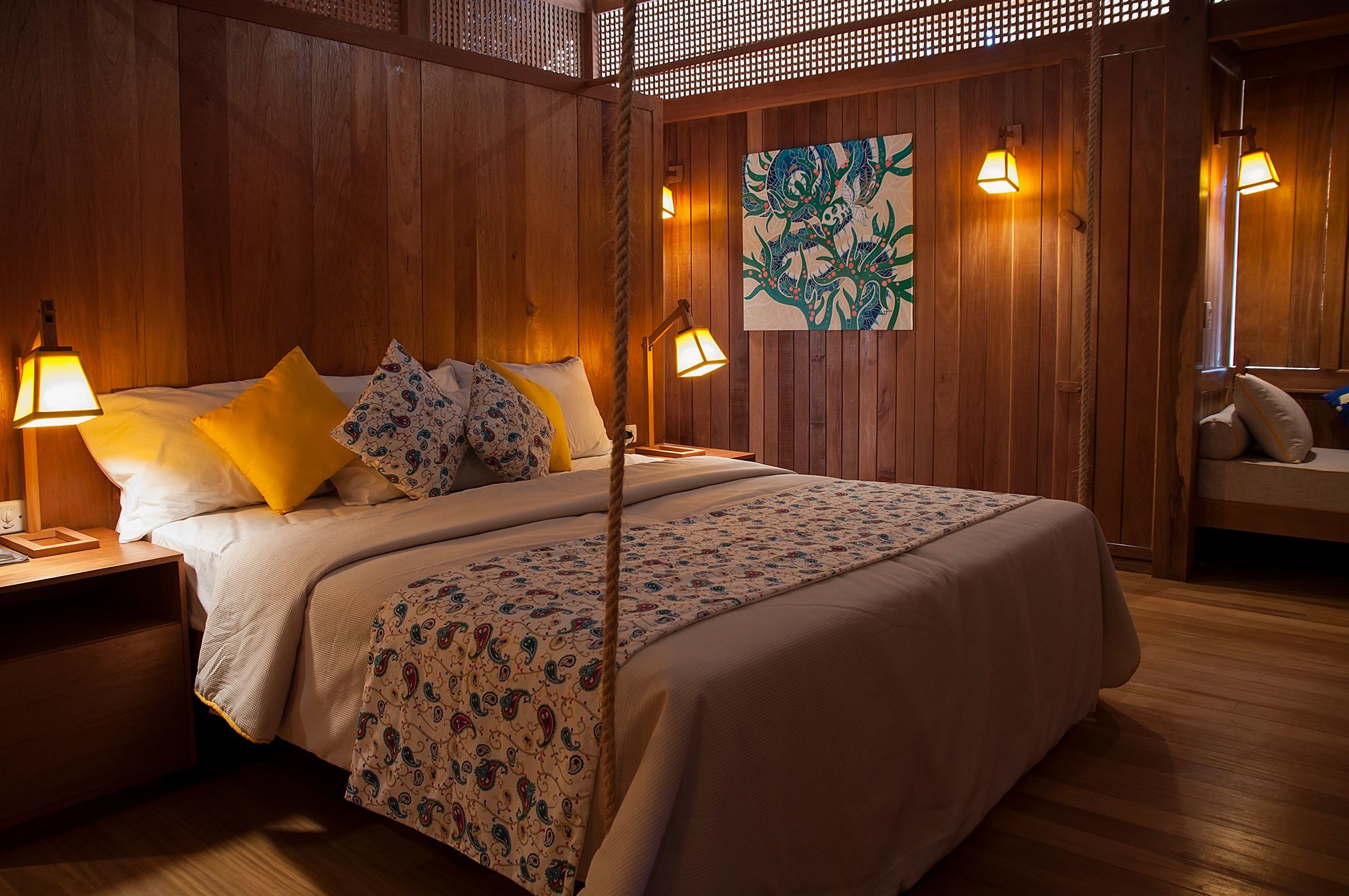 A wooden-paneled room with a bed, two bedside lamps, and a wall-mounted artwork.
