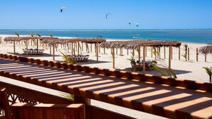 Une plage avec des parasols en chaume et des bancs en bois, offrant une vue sur la mer.
