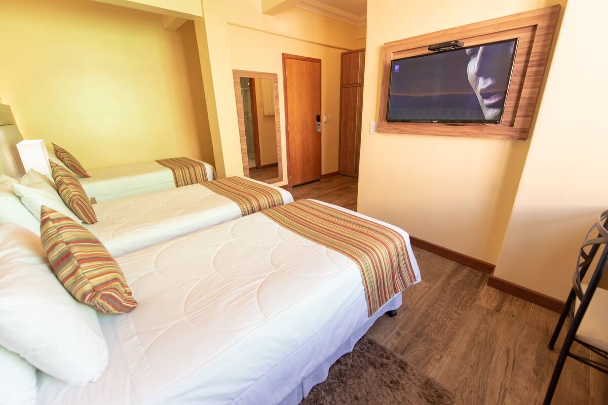 A hotel room with two beds, a TV mounted on the wall, and a wooden door.