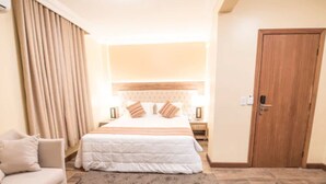A hotel room with a bed, a nightstand, a chair, a wooden door, and a carpeted floor. - Hotel Alles Blau (Pelotas)