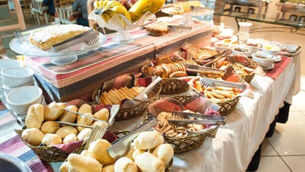 A buffet table with various food items including bread, pastries, and fruits. - Hotel Alles Blau (Pelotas)