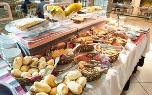 Een buffet met diverse gerechten, waaronder brood, gebak en fruit.