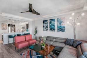A modern living room with a sofa, a coffee table, and a kitchen in the background.