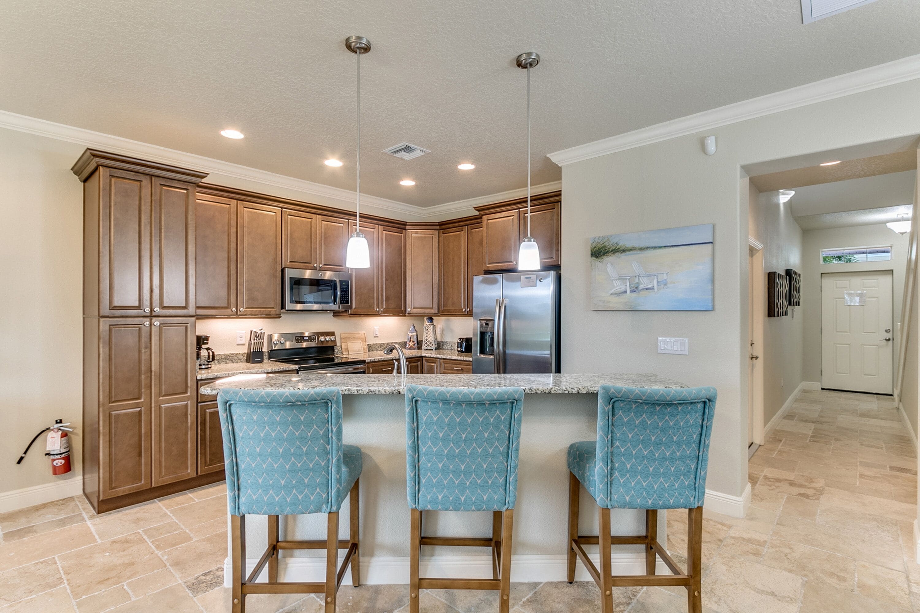 A modern kitchen with wooden cabinets, stainless steel appliances, and a central island with bar stools.
