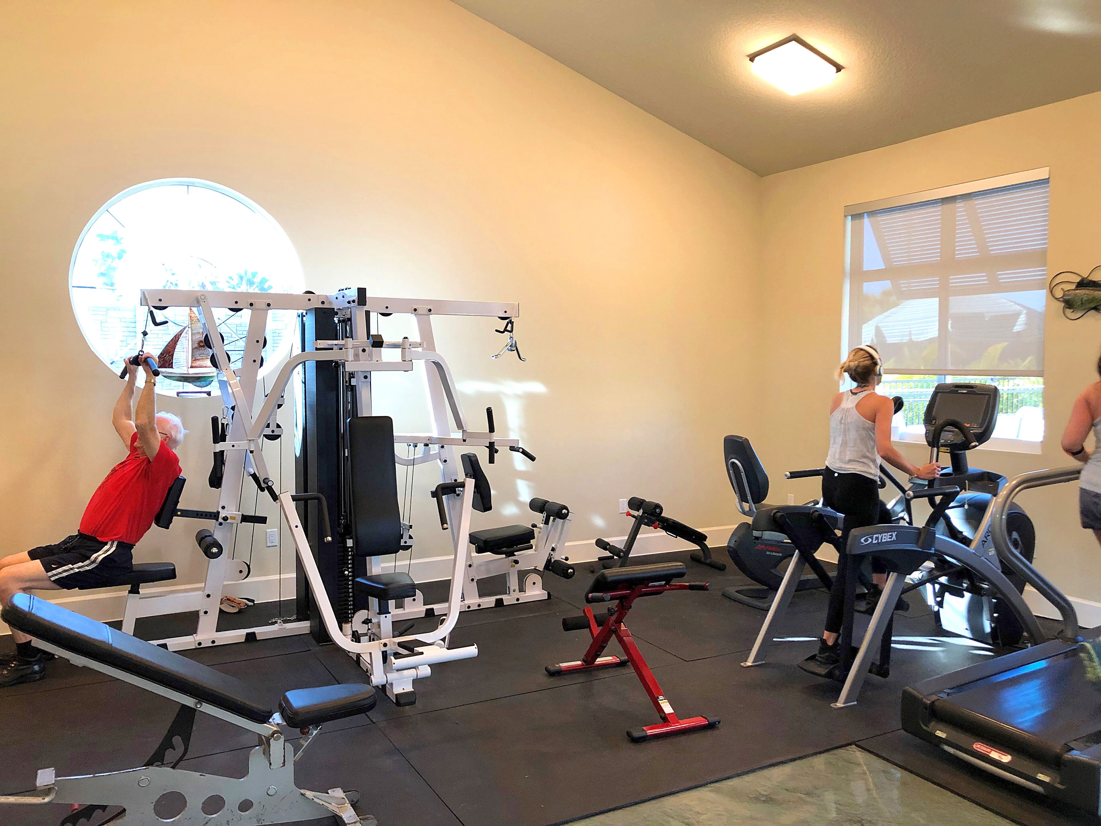 A gym with various exercise equipment, including a bench press, a squat rack, and treadmills.