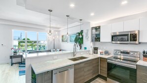 A modern kitchen with a large island, stainless steel appliances, and a view of the outdoors.