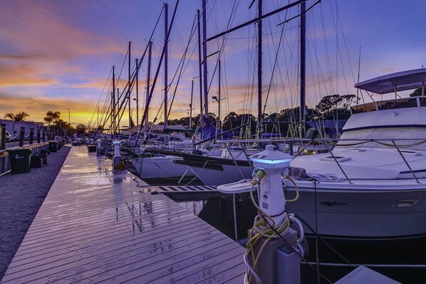 Un puerto deportivo con varias embarcaciones amarradas a muelles de madera al atardecer.