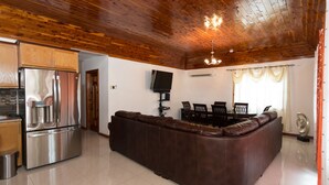A modern kitchen with a stainless steel refrigerator, a built-in oven, and a dining area with a brown leather sofa and a dining table. - New Kingston Guest Apt at Fairway (Kingston)