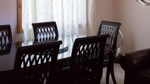 A dining area with a wooden ceiling, a chandelier, a round mirror, and a dining table with chairs. - New Kingston Guest Apt at Fairway (Kingston)
