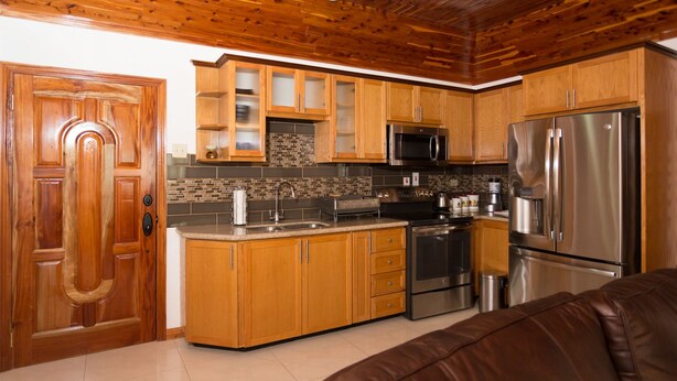 A kitchen with wooden cabinets, a stainless steel refrigerator, a microwave, and a stove. - New Kingston Guest Apt at Fairway (Kingston)