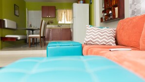 A living room with a sofa, ottoman, and a remote control on it. - The Hellshire Beach House (Hellshire)