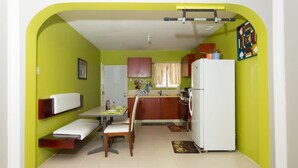 A compact kitchen with a dining area, a refrigerator, and a window with curtains. - The Hellshire Beach House (Hellshire)