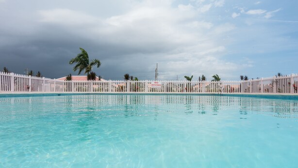 A clear blue pool surrounded by a white fence with palm trees and a 'NO DIVING' sign. - The Country Club Villa I (Kingston)