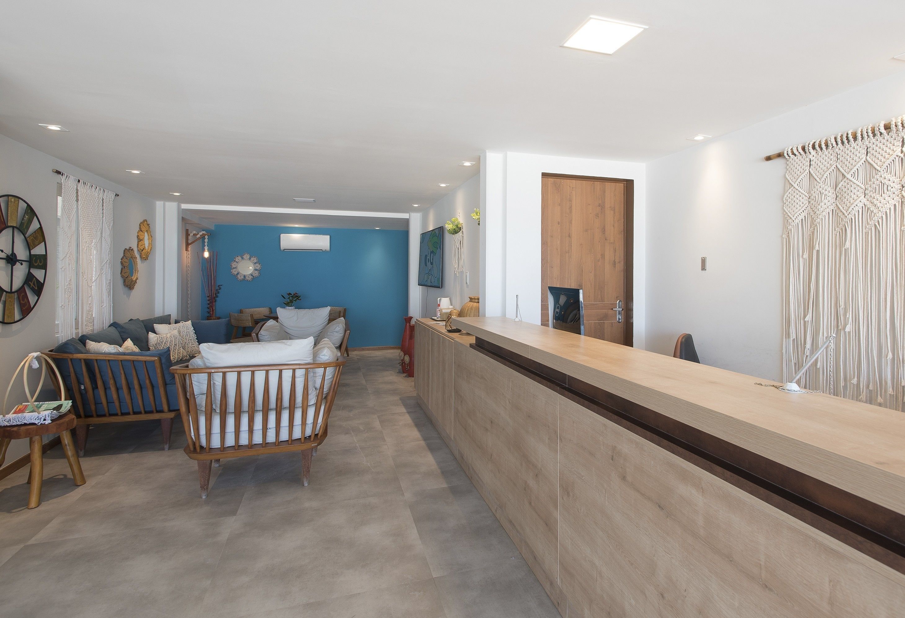 Ein moderner Empfangsbereich mit einer Holztresen, einer blauen Wand und einer Sitzecke mit einer Couch und einem Reisebett.