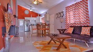A modern living room with a sofa, coffee table, and a dining area with chairs and a table. - The Country Club Villa II (Kingston)