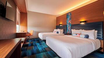 A hotel room with two beds, a desk, and a chair.