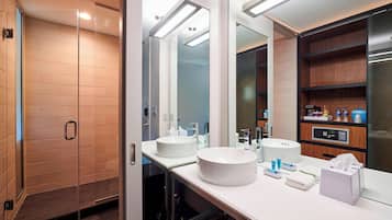 A modern bathroom with two sinks, a glass shower enclosure, and a large mirror.