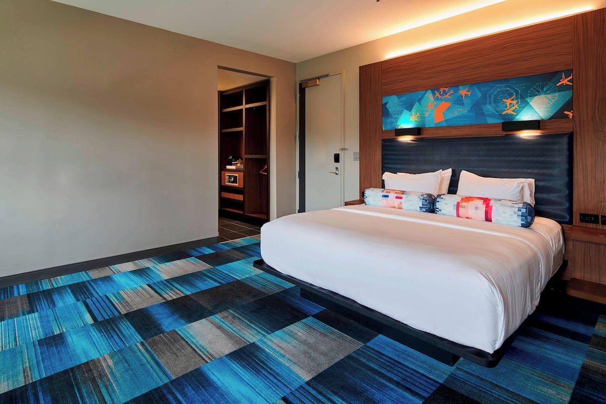 A hotel room with a large bed, a walk-in closet, and a wall-mounted TV.