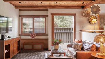 A cozy living room with wooden beams, a leather sofa, a coffee table, and a TV.