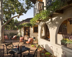 Une terrasse avec des meubles d’extérieur, une table avec une bouteille de vin et une plante en pot.