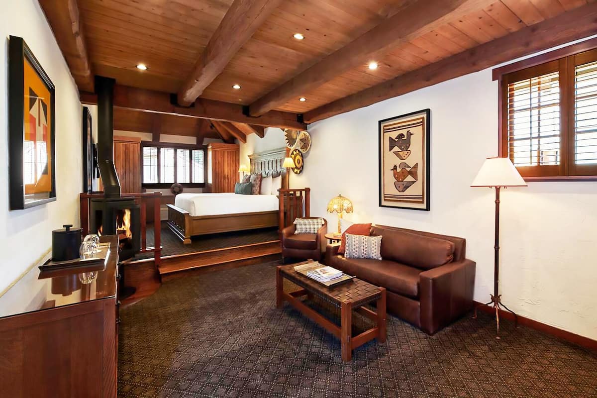 A cozy living room with a fireplace, a bed, a sofa, and a coffee table.