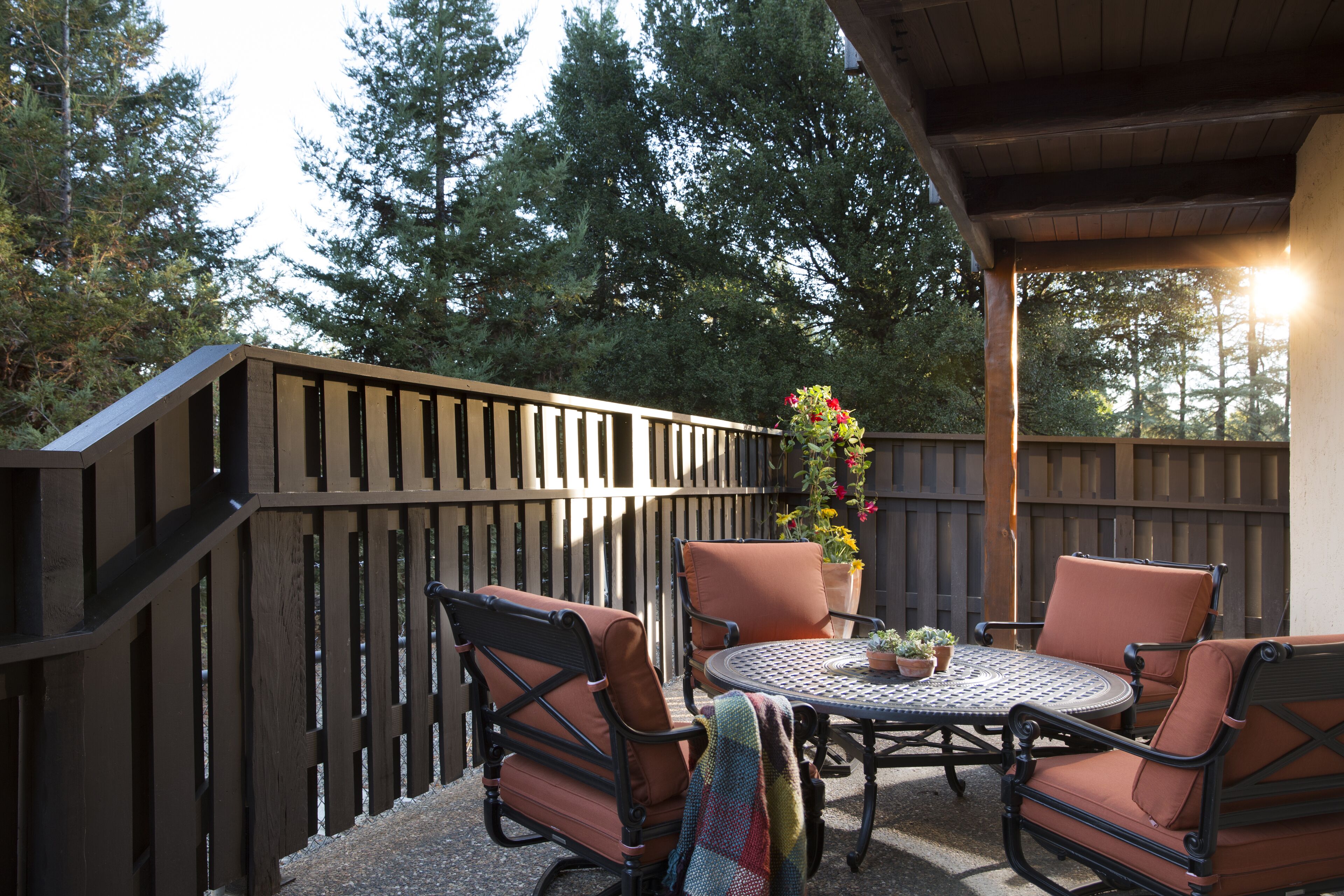 An outdoor patio with a wooden fence, a round table, and two chairs.