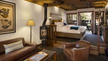 A cozy room with a bed, a sofa, a chair, a table, and a fireplace.