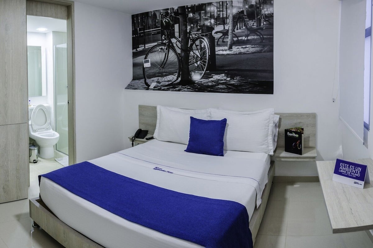 Ein modernes Hotelzimmer mit einem großen Bett, einem Badezimmer und einem Stadtbild.