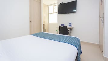 Ein Hotelzimmer mit Bett, Schreibtisch, Stuhl, Fernseher und Fenster.