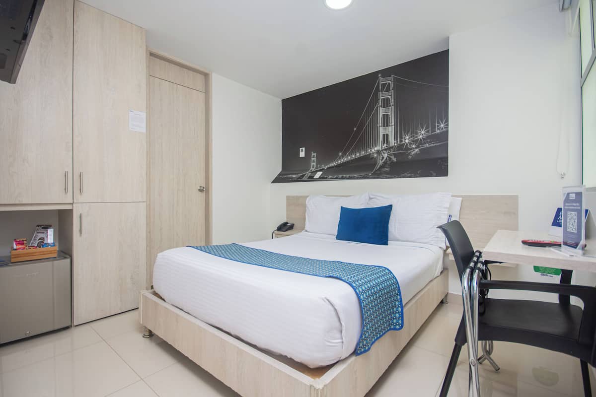 Ein Hotelzimmer mit Bett, Schreibtisch, Stuhl und Kleiderschrank.