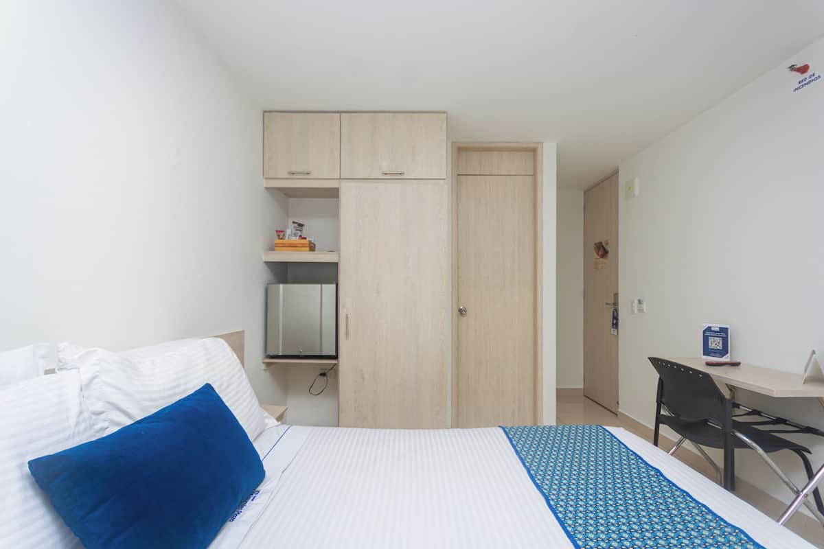 Ein Hotelzimmer mit Bett, Schreibtisch, Stuhl und Kleiderschrank.
