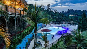 Uma área de piscina com um mural, rodeada por vegetação exuberante e palmeiras.