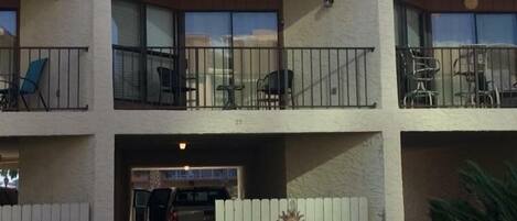 A multi-story building with balconies, outdoor seating, and a gated entrance.