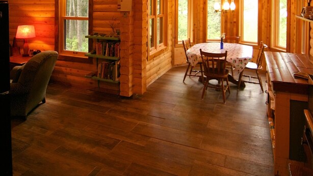 A log cabin interior with a dining area, a fireplace, and a large window.