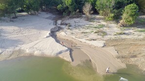 Une rive de rivière avec un sentier sablonneux et un petit plan d'eau.