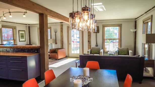 A modern kitchen with a central island, dining area with a table and chairs, and a living room with a sofa and a chandelier. - No hidden cleaning charges.  Huge 3bd/3ba apartment with tons of waterviews. (Belfast)