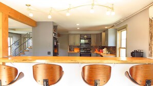 A modern kitchen with a central island, bar stools, and a staircase leading to an upper level. - No hidden cleaning charges.  Huge 3bd/3ba apartment with tons of waterviews. (Belfast)